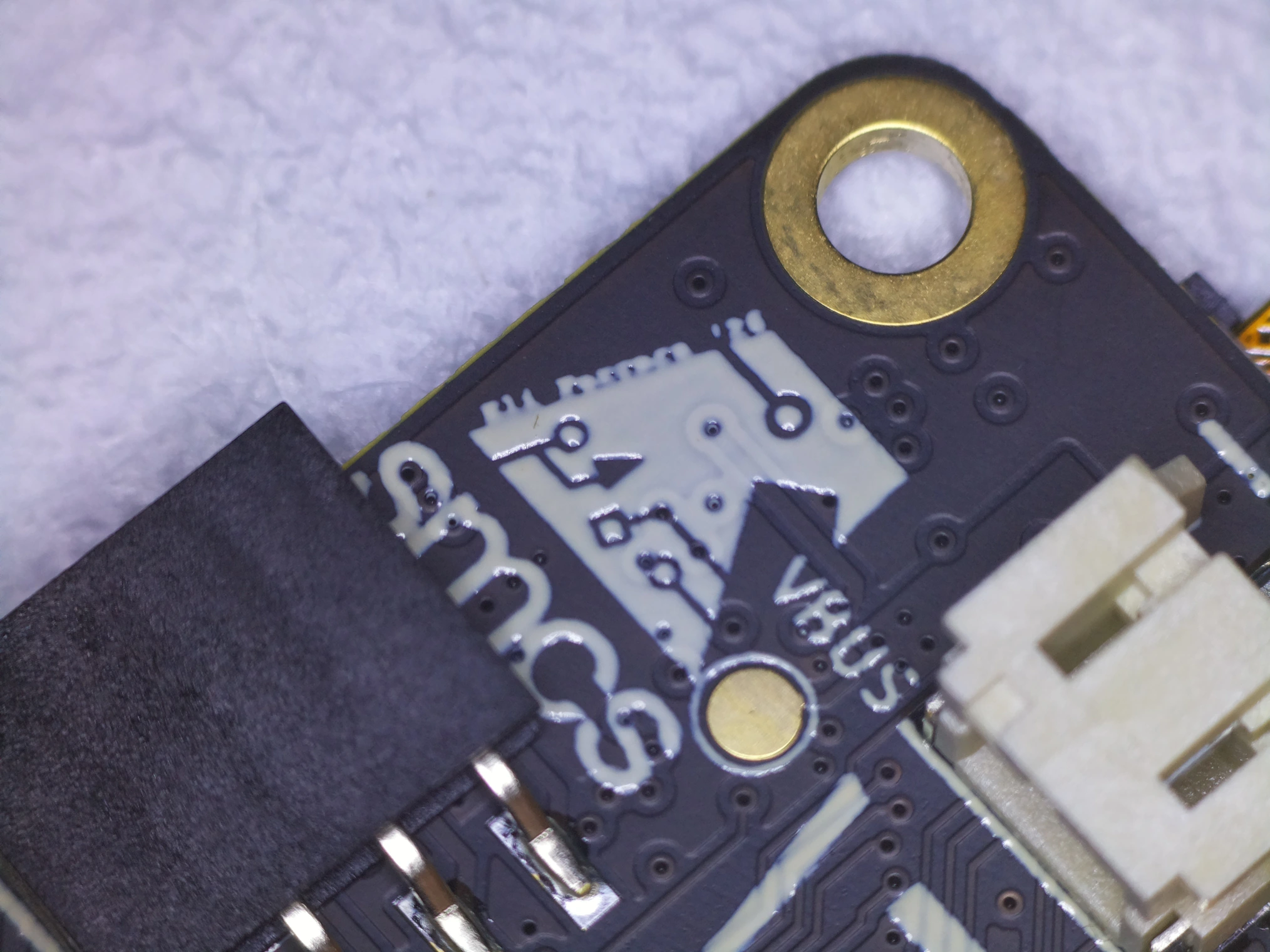 SMCS Logo next to gold-plated mounting holes, contrasted against a matte black soldermask